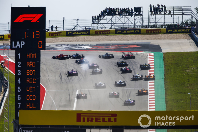 Kimi Raikkonen, Ferrari SF71H, passes Lewis Hamilton, Mercedes AMG F1 W09 EQ Power+, in the first turn as they lead the field at the start of the race