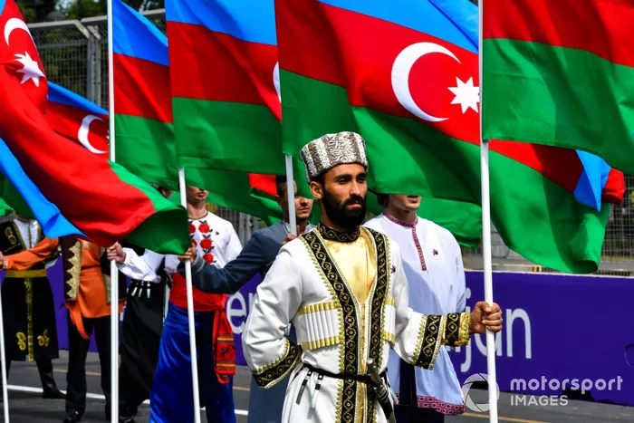 Artistas con trajes tradicionales con banderas de Azerbaiyán en la parrilla