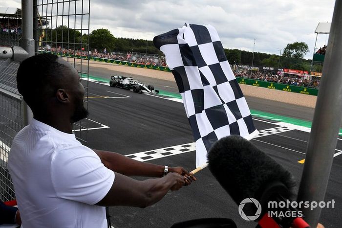 Stormzy, Rapero ondea la bandera de llegada mientras Lewis Hamilton, Mercedes AMG F1 W10 cruza la línea