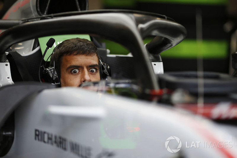 A Haas mechanic sits in the cockpit of a Haas F1 Team VF-18