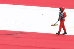Un oficial de pista con una escoba barre residuos en el circuito
