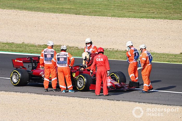 Los oficiales se reúnen alrededor del monoplaza parado de Sebastian Vettel, el Ferrari SF1000