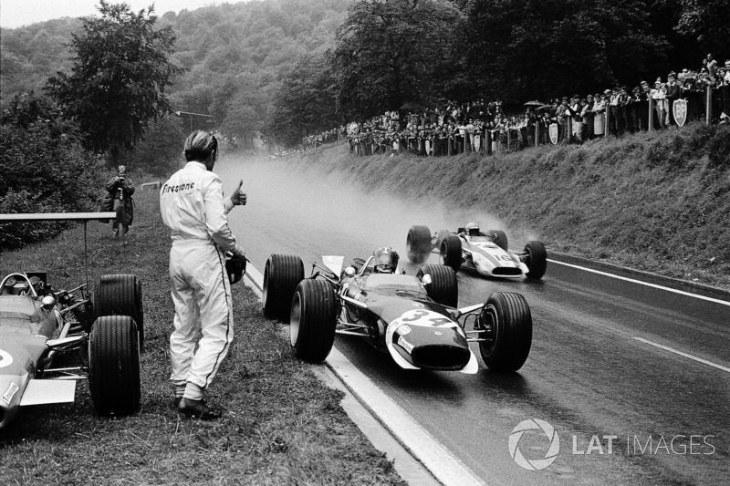 Jo Siffert, Lotus has just stopped for borrowing a dry visor from retired Graham Hill. John Surtees, Honda is passing the pair