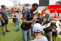 Daniel Ricciardo, Red Bull Racing, signs autographs for young fans as Romain Grosjean, Haas F1 Team, looks on