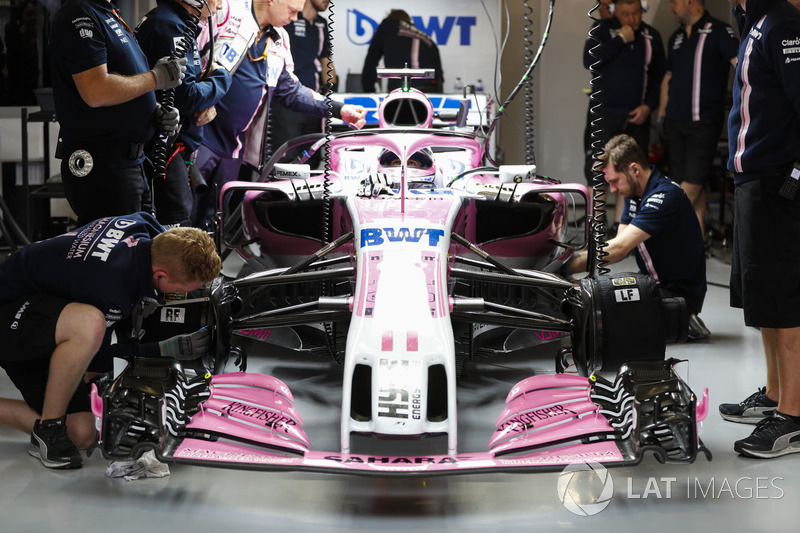 Engineers work on the car of Sergio Perez, Force India VJM11, in the garage whilst he sits in the co