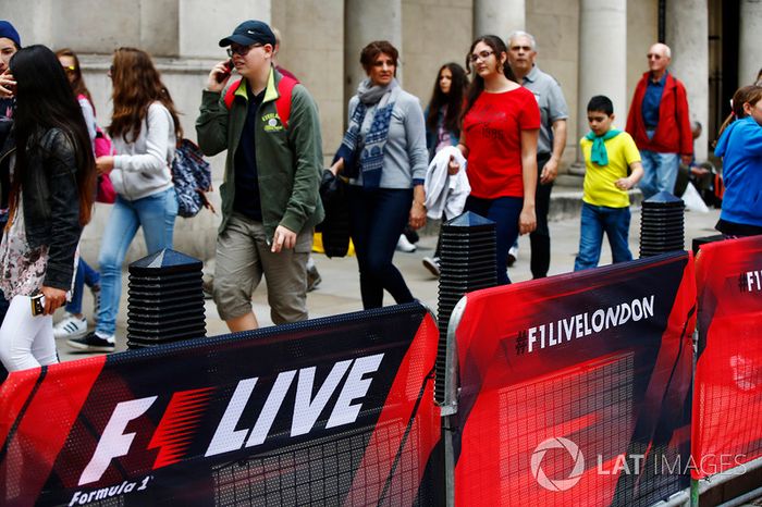 Los miembros del público a pie pasando barandas cubiertas de  F1 Londres