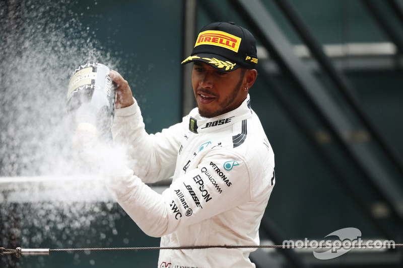 Lewis Hamilton, Mercedes AMG, celebrates victory by spraying chamagne on the podium