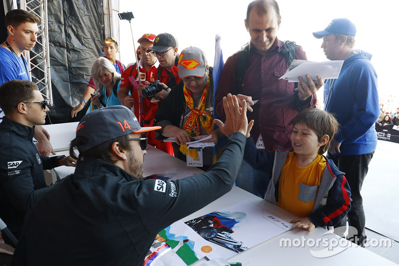 Fernando Alonso, McLaren, give a high-five to a young fan, as Stoffel Vandoorne, McLaren, signs autographs