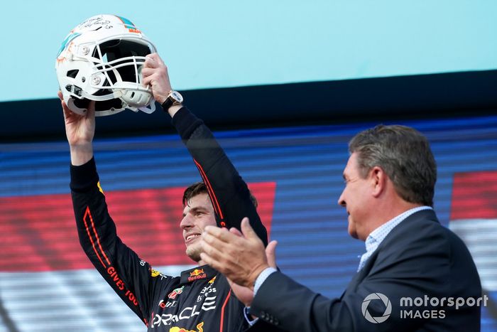 Max Verstappen, Red Bull Racing, 1ª posición, recibe un casco de fútbol de los Miami Dolphins en el podio