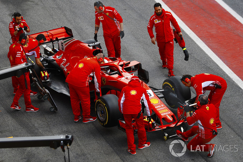 Sebastian Vettel, Ferrari SF71H, is attended to by mechanics in the pit lane