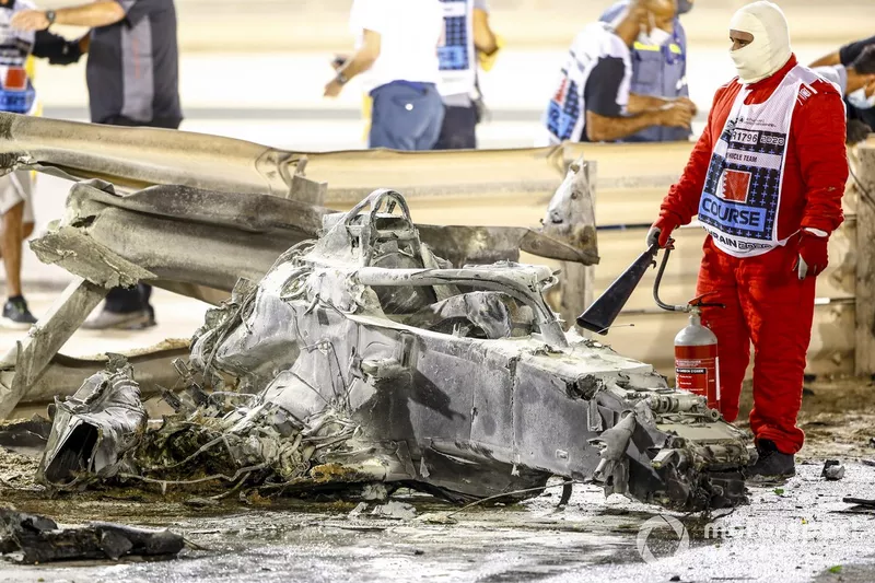 A fire marshal with wreckage after a huge crash for Romain Grosjean, Haas VF-20, on the opening lap