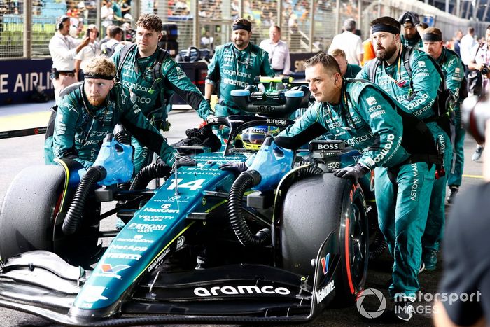 Los mecánicos llevan a Fernando Alonso, Aston Martin AMR23, a la parrilla de salida