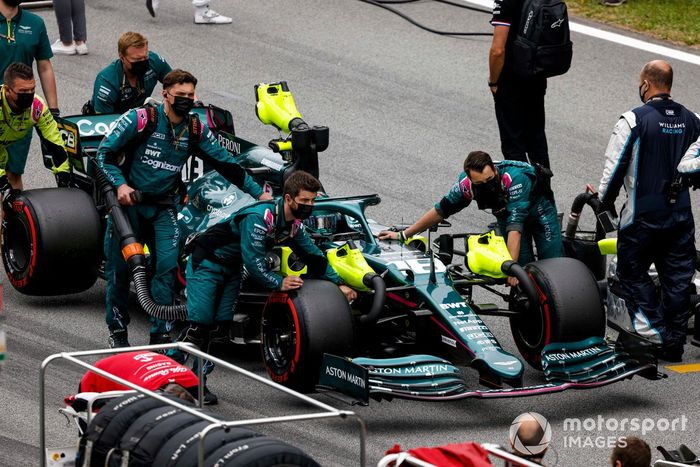 Los mecánicos mueven a Lance Stroll, Aston Martin AMR21, a su posición en la parrilla