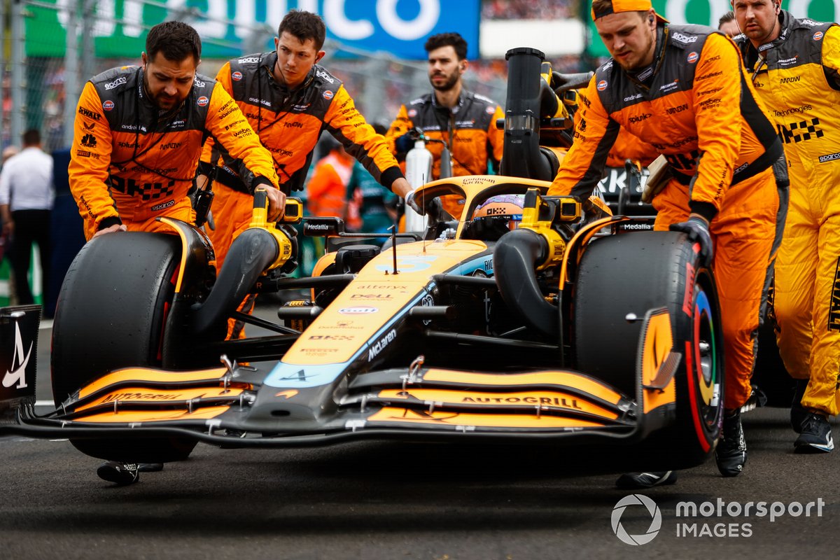 Des mécaniciens poussent la McLaren MCL36 de Daniel Ricciardo.