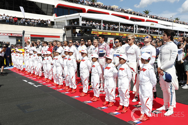 Piloti e Grid Kid osservano l'inno nazionale prima della partenza della gara