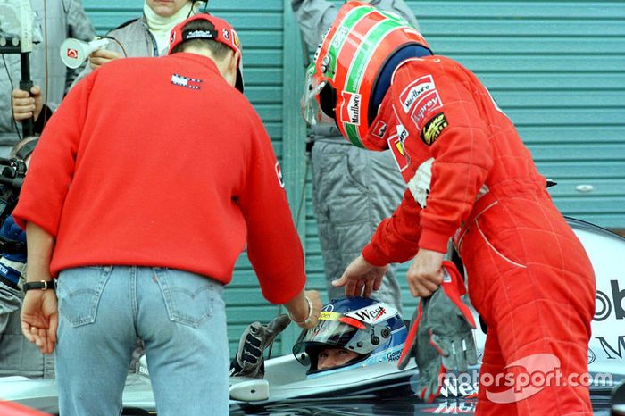 Pilotos de Ferrari Michael Schumacher y Eddie Irvine felicitan al nuevo campéon de Fórmula Uno Mika Hakkinen, McLaren