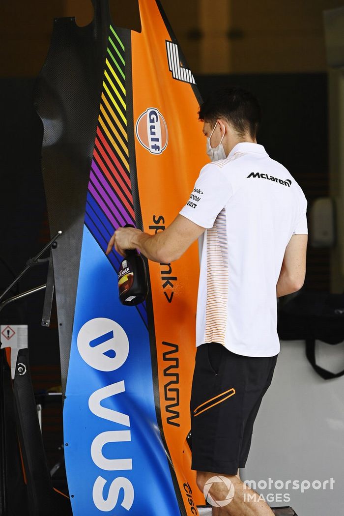 Un miembro del equipo McLaren limpia una pieza de carrocería en el pit lane