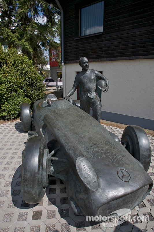 A bronze statue of Juan Manuel Fangio and his Mercedes-Benz W196 at the track entrance